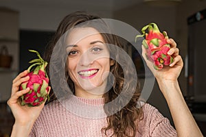 Young girl is holding two fresh ripe organic dragon fruits or pitaya, pitahaya. Exotic fruits, healthy eating concept