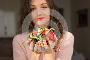 Young girl is holding two fresh ripe organic dragon fruits or pitaya, pitahaya. Exotic fruits, healthy eating concept