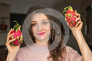Young girl is holding two fresh ripe organic dragon fruits or pitaya, pitahaya. Exotic fruits, healthy eating concept
