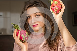 Young girl is holding two fresh ripe organic dragon fruits or pitaya, pitahaya. Exotic fruits, healthy eating concept