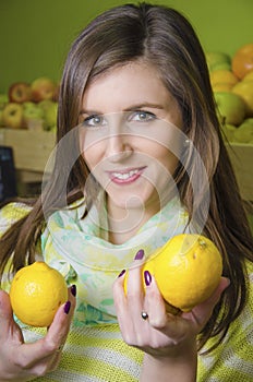 Young girl holding two lemons in greengrocery photo