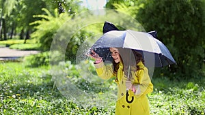 Young girl holding an umbrella and playing in the rain