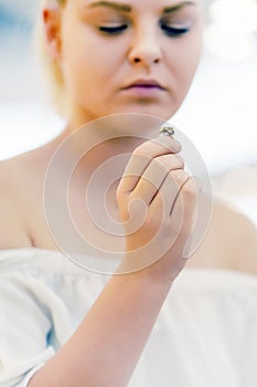 Young girl holding a wedding ring doubtfully