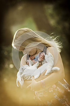 Young girl is holding white rabbit