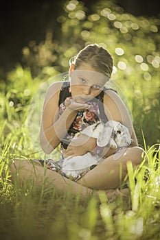 Young girl is holding white rabbit