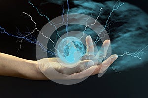 A young girl holds a ball of lightning in her hand against a dark background of blue misty clouds. The concept of