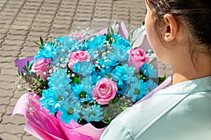 Young girl holds a bouquet of blue and rose flowers. Present for Birthday, Women `s day or Valentine `s day