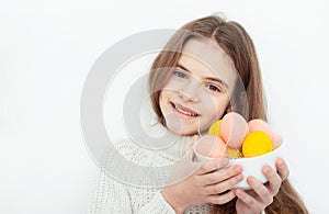 Young girl holds bowl with colorful eggs white background right