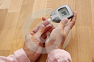 Young girl holds a glucometer for measuring blood sugar in both hands and makes a finger test, medical concept, diabetic, close-up