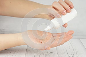 A young girl holds in her palms a small white bottle with cosmetic or perfume, drips into her palm