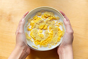 Young girl holds plate with milk and corn flakes