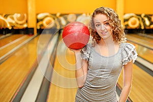 Young girl holds red ball in bowling club
