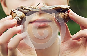 Young girl holds two snails which turn to one to one.