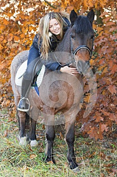 Young girl on horseback stroking a horse