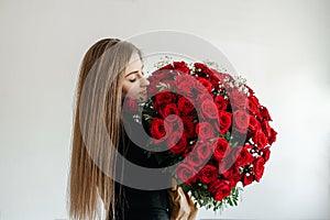 A young girl with a huge bouquet of red roses. Happy woman smelling flowers. Gifts for holidays and birthdays
