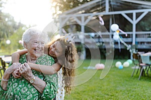 Young girl hugging her elderly grandmother at a garden party.