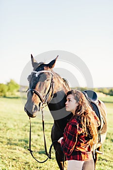 Young girl hugging purebred black horse on the field.