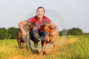 Young girl hugs two boxer dogs