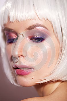 Young girl in the image of a fantasy with a piercing. Beautiful model in a white wig with bob and bright makeup. Beauty face.