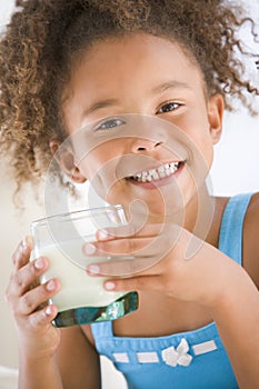 Young girl indoors drinking milk smiling