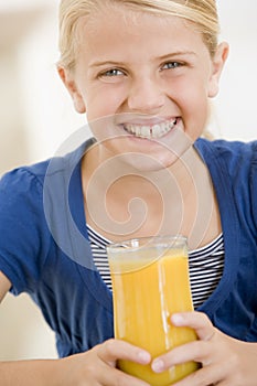Young girl indoors drinking orange juice