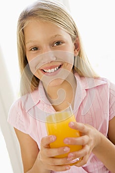 Young girl indoors drinking orange juice smiling