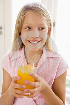 Young girl indoors drinking orange juice smiling