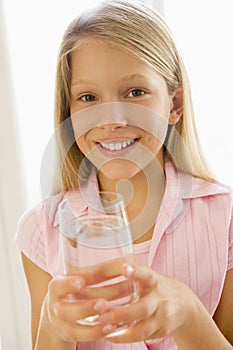 Young girl indoors drinking water smiling