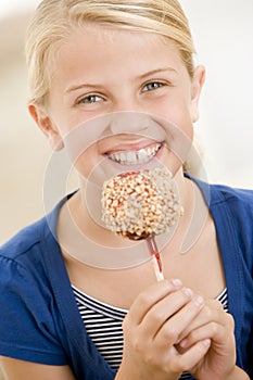 Young girl indoors eating candy apple