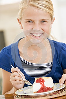 Young girl indoors eating cheesecake