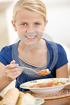 Young girl indoors eating soup