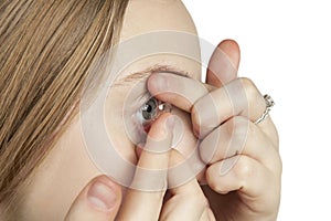 A young girl inserts contact lenses