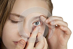 A young girl inserts contact lenses into her eyes