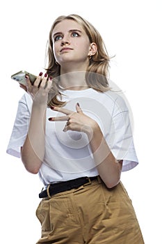 A young girl is irritably talking on the phone. A teenager in beige trousers and a white T-shirt. Stress and negative reaction.