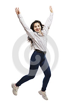 A young girl in jeans and a white shirt is jumping. Smiling brunette with long hair. Movement and energy. Isolated on a white