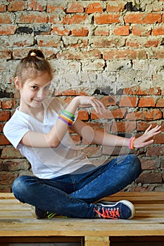 Young girl in jeans and white T-shirt is sitting on the floor and dance. Concept portrait of a pleasant friendly happy  teenager