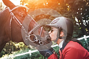 A young girl jockey talking to her horse. She loves the animals and joyfully spends her time in their environment