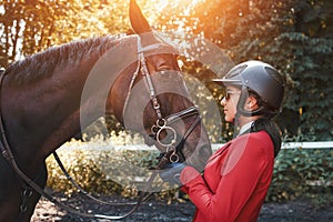 A young girl jockey talking to her horse. She loves the animals and joyfully spends her time in their environment