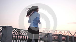 Young girl jogging along the deserted embankment in the early morning. beautiful sportswoman exercising outdoors.