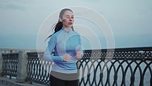 Young girl jogging along the deserted embankment in the early morning. beautiful sportswoman exercising outdoors.