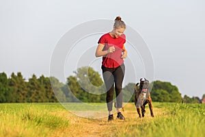 Young girl jogs with a boxer dog