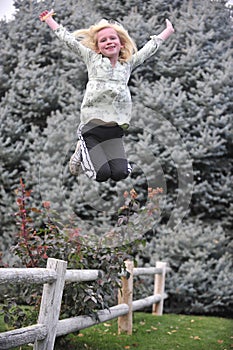 Young girl jumping from a fence