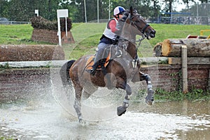 Young girl jumping obstacle with dapple grey horse