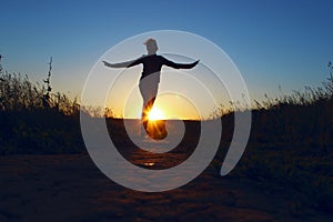 Young Girl Jumping Over Sunset Background. Full Length Silhouette Of A Happy Girl  Running Outdoors.