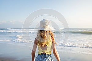 Young girl jumping and running waves at beach on sunset time.