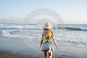 Young girl jumping and running waves at beach on sunset time.