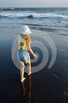 Young girl jumping and running waves at beach on sunset time.