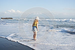 Young girl jumping and running waves at beach on sunset time.