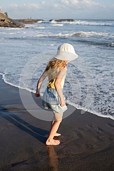 Young girl jumping and running waves at beach on sunset time.