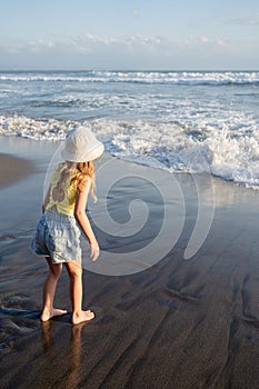 Young girl jumping and running waves at beach on sunset time.